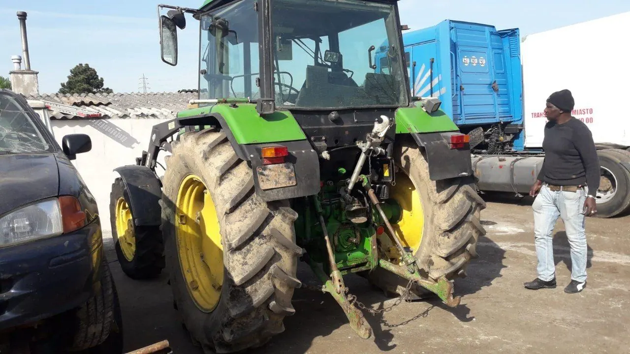 Green John Deere tractor in a yard, being prepared for shipping